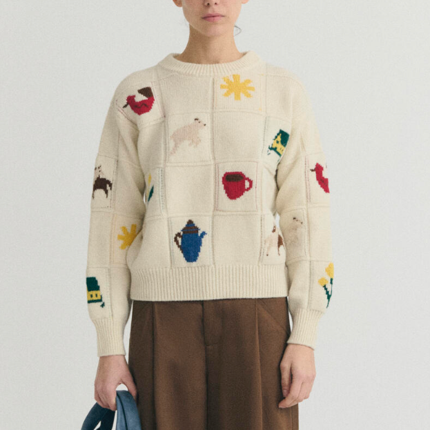 A cream knit sweater with colorful embroidered motifs.