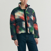 A model wearing a colorful abstract-patterned puffer jacket with dark blue jeans.
